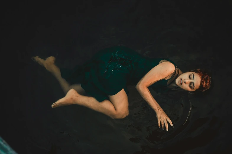 an orange - haired woman floating down in water