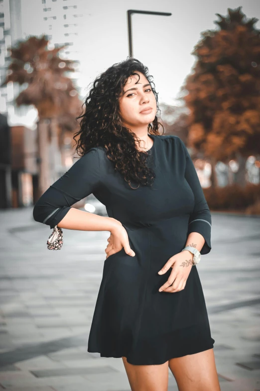 a woman poses for a picture wearing a short black dress