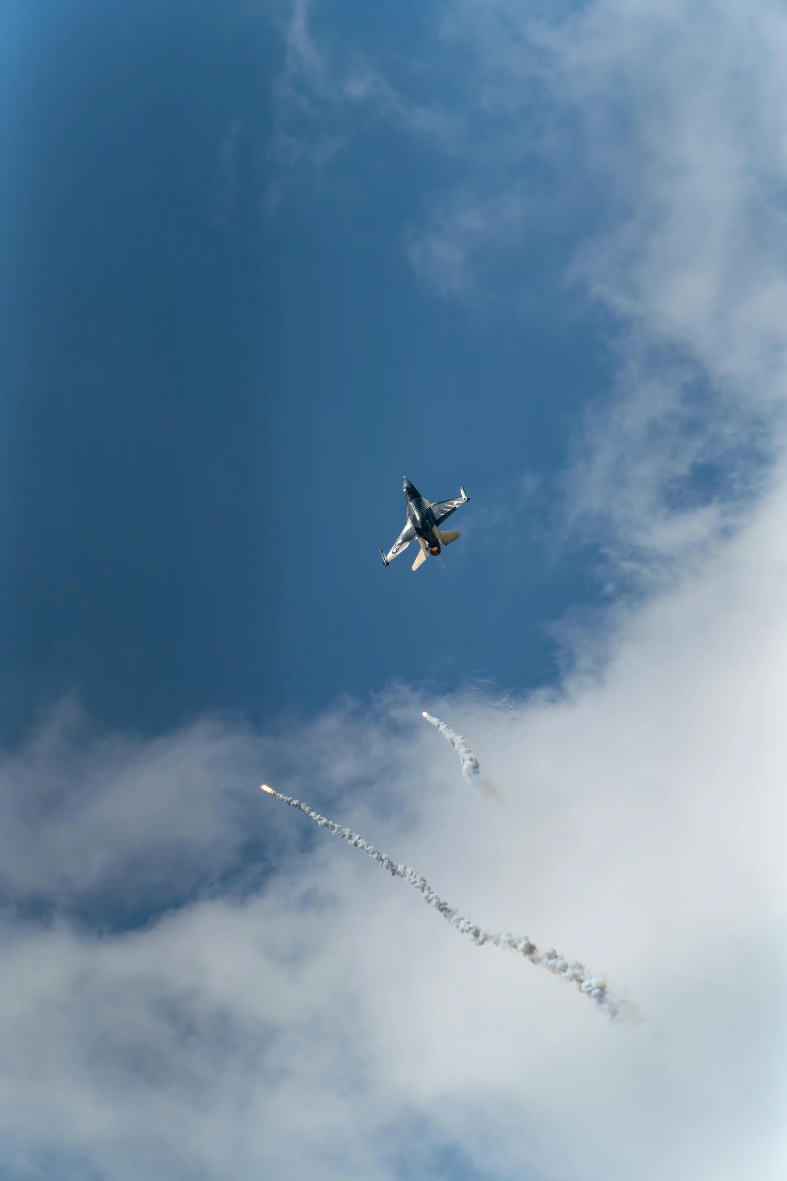 an airplane flies through the sky with contrails in front