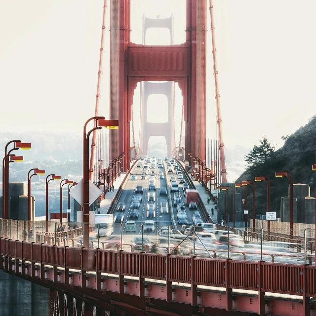 a red and yellow bridge over water with cars passing under