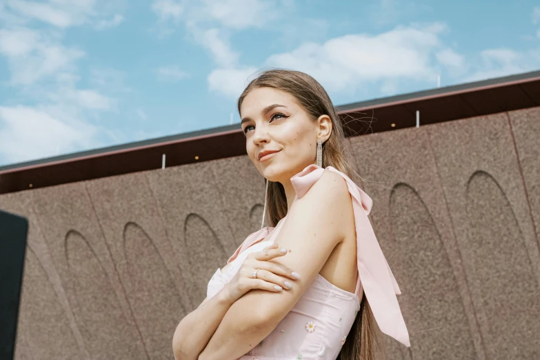 a girl in a pink top poses in front of a building