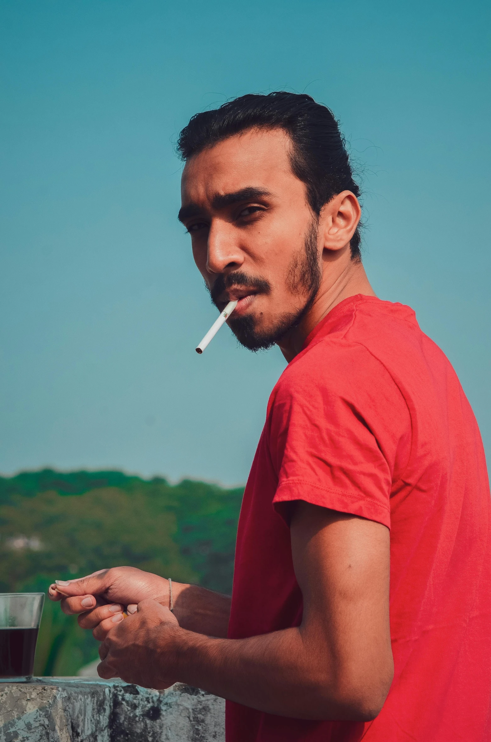 a man smokes a cigarette while standing in front of a lake