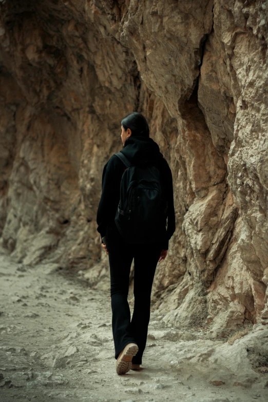 a man is walking along a trail between rocky mountains