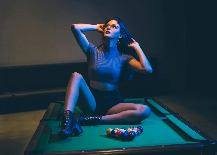a woman is sitting on top of a pool table