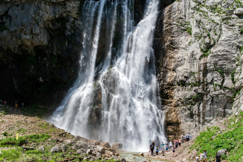 several people walking near a waterfall as it pours