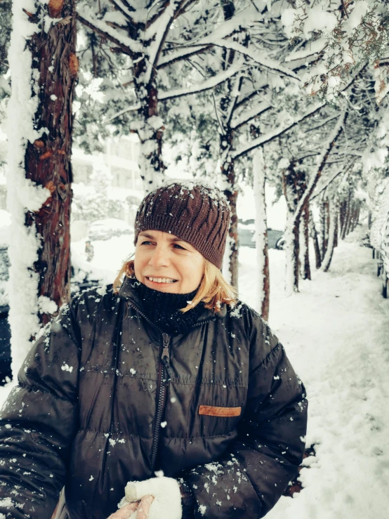 a woman in her brown jacket is posing in the snow