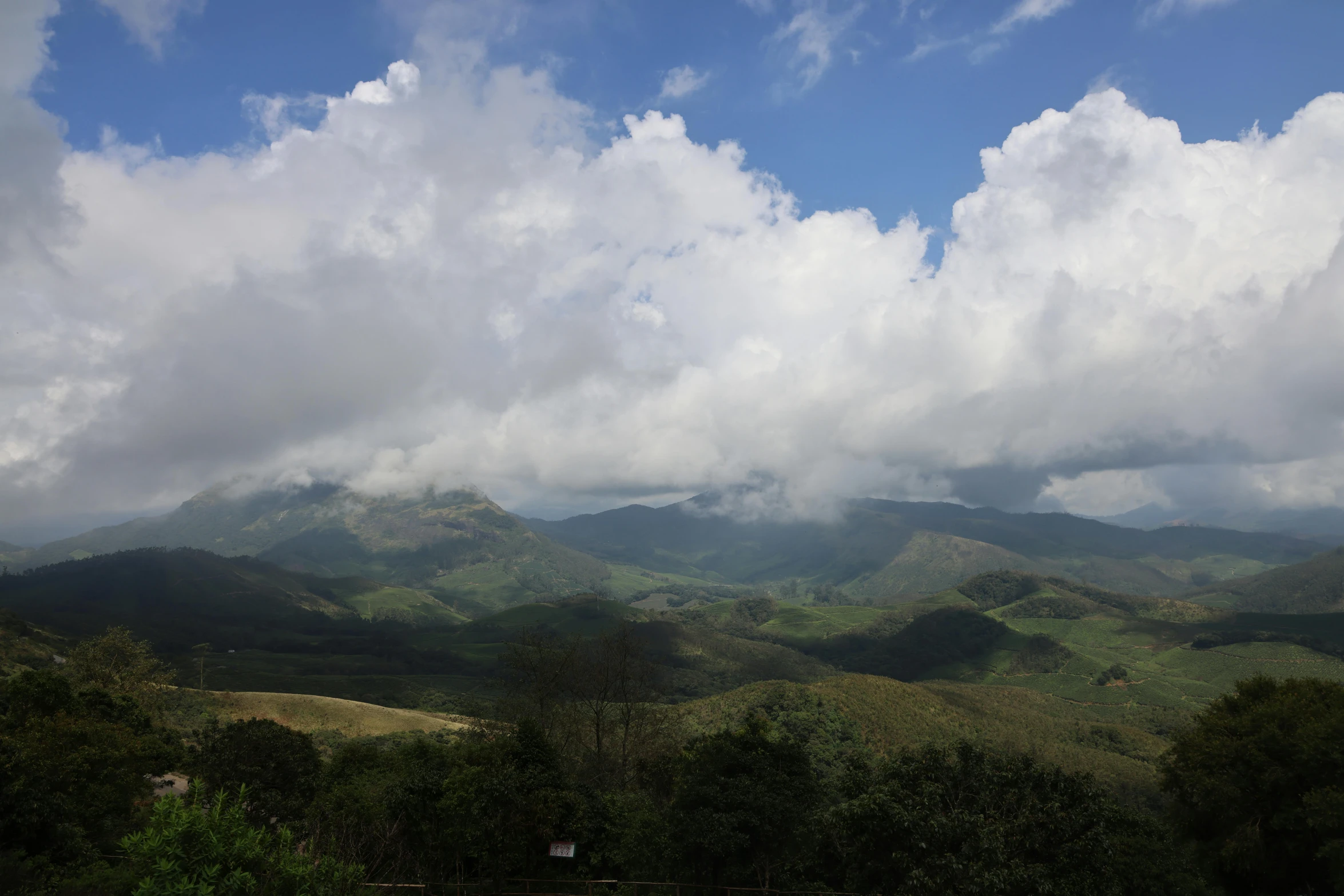 some clouds are rolling over some green mountains