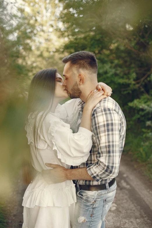 the man and woman are kissing on a dirt road