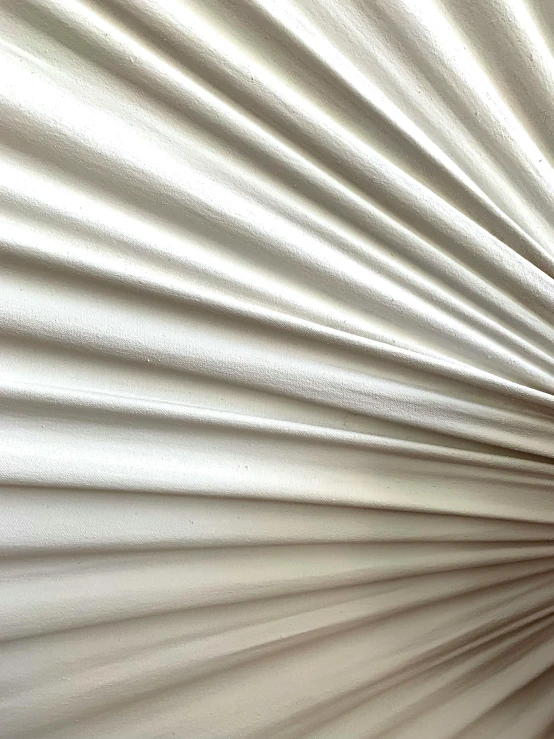 a long white sheet with its long shadow on the wall