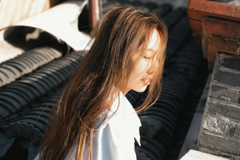 a little girl with long hair standing in front of piles of tires