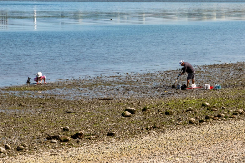 people on the shore of an ocean with small boats