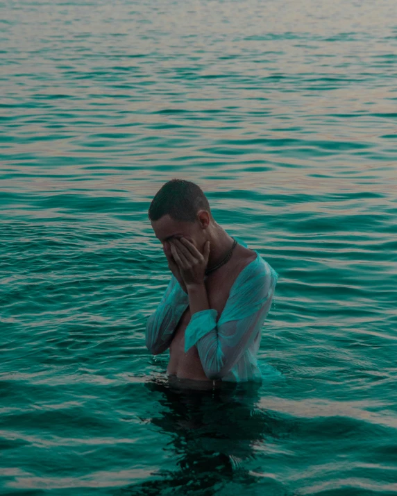 a man with his hand to his face floating in the water