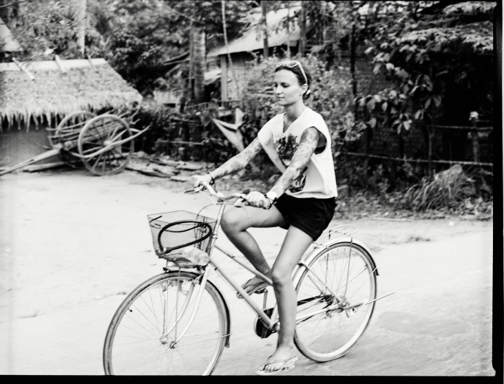 a woman riding a bike down a street past houses