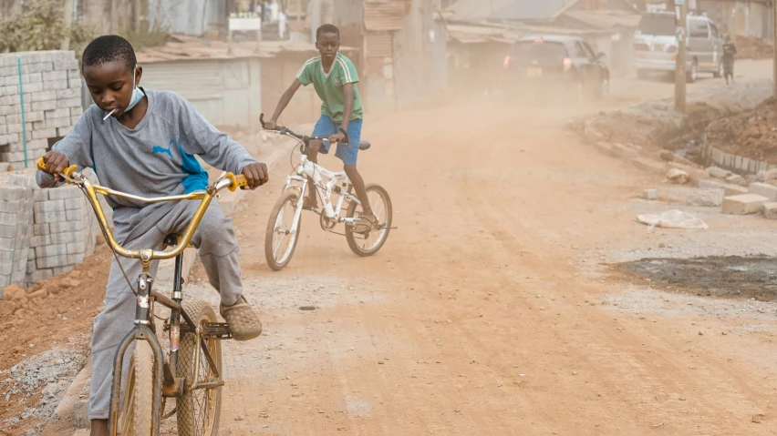 two children on bikes are riding down a dirt road