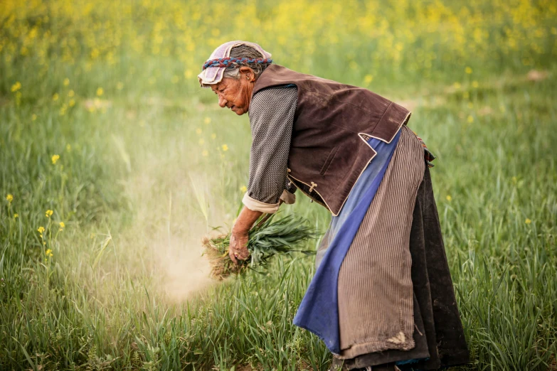 a woman is bending over picking up some grass