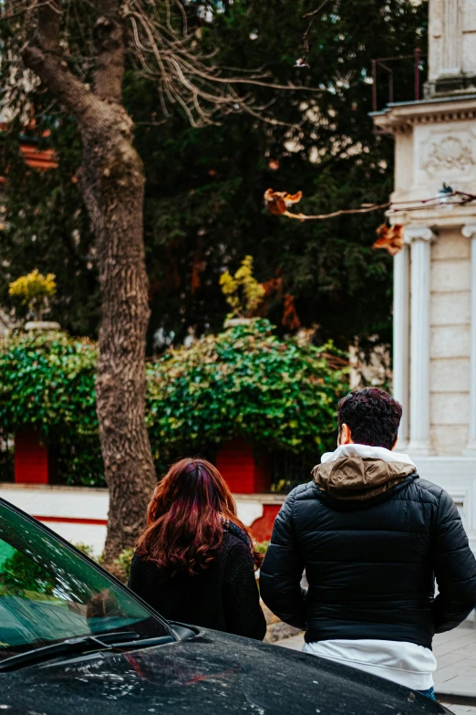 two people are walking next to their car