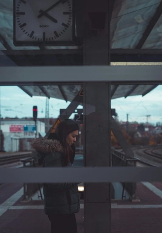 a lady looking through a window at the railroad tracks