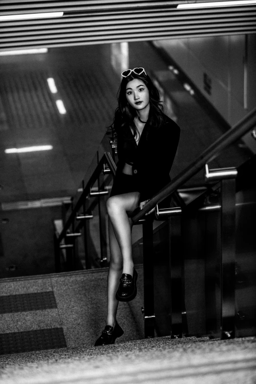 black and white pograph of woman in short dress sitting on stairs