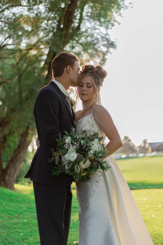 a bride and groom standing together in the grass