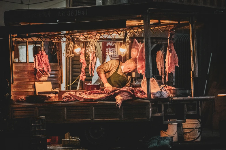 a man working inside of a stand selling meat