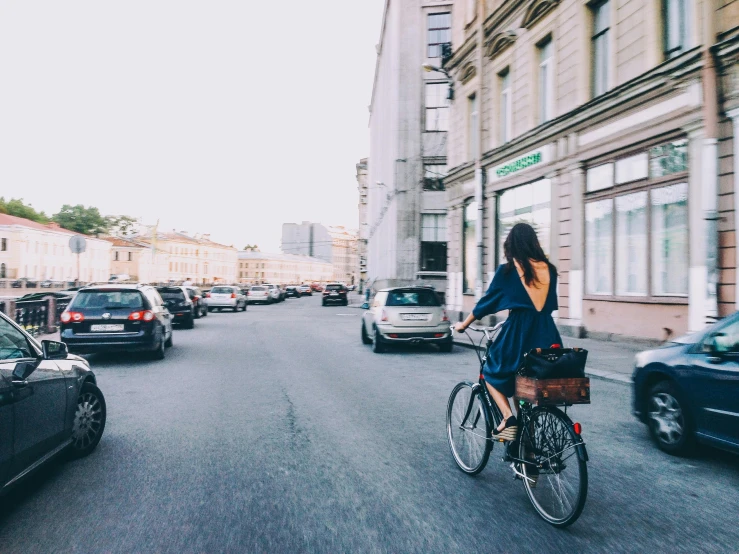 a girl with a basket riding a bicycle down a street