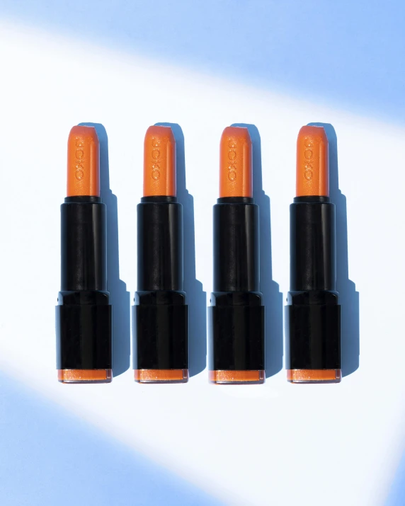 three orange lipsticks and a brown bag