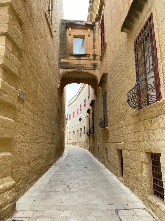 a narrow alley with cobblestone streets and arched windows