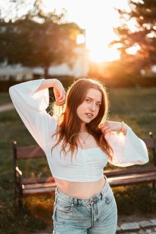 a young woman is posing in front of a bench