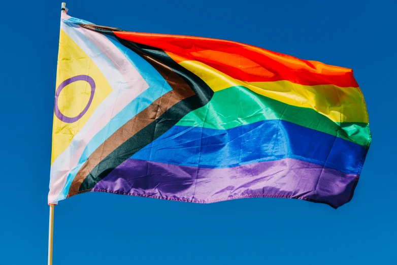 a rainbow flag against a blue sky