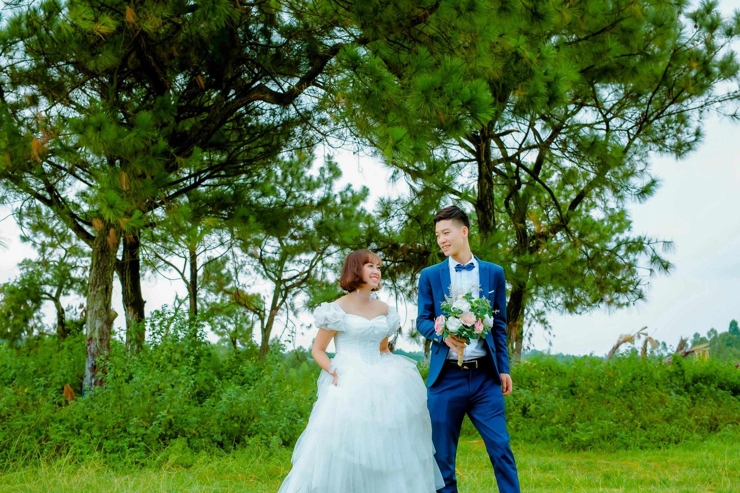 the bride and groom are standing together near a forest