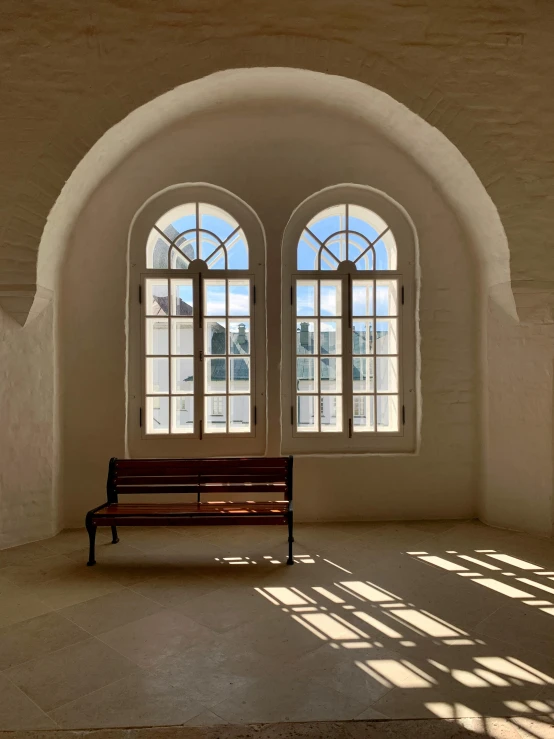 a bench sitting in front of two double - hung windows