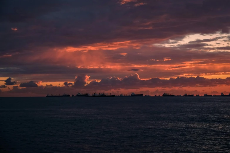 a sunset over the ocean with a few ships in the background