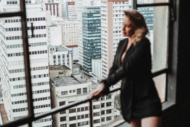 a woman looking out a window with the city in the background