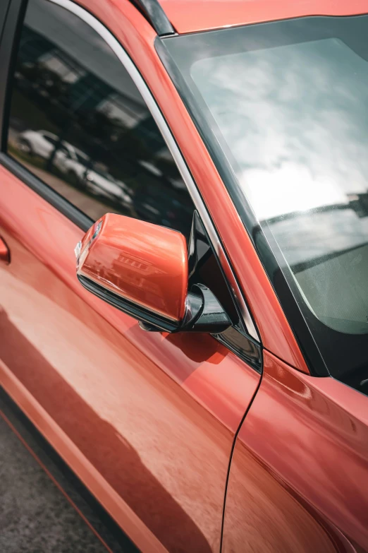 side view mirror showing that the side mirrors of a red car are slightly left handed