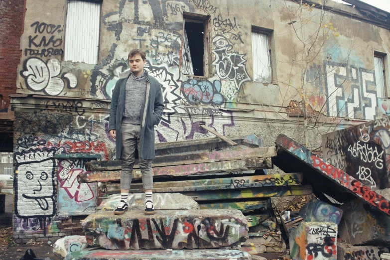 man standing on part of a building covered with graffiti