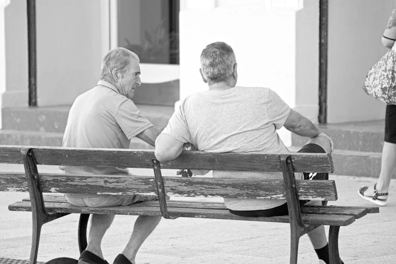 two men sitting on a bench talking to each other