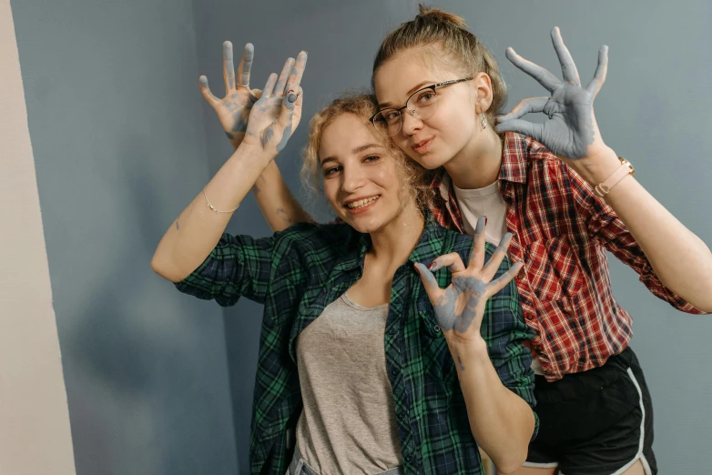 two women standing next to each other with painted hands