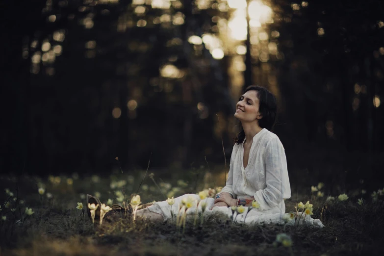 a woman is meditating in the middle of the woods