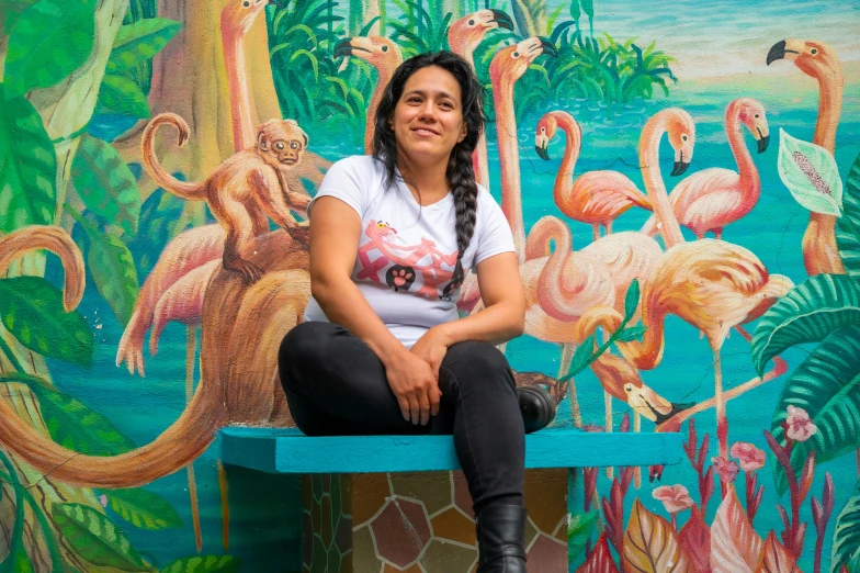 woman sitting on a bench in front of a colorful mural