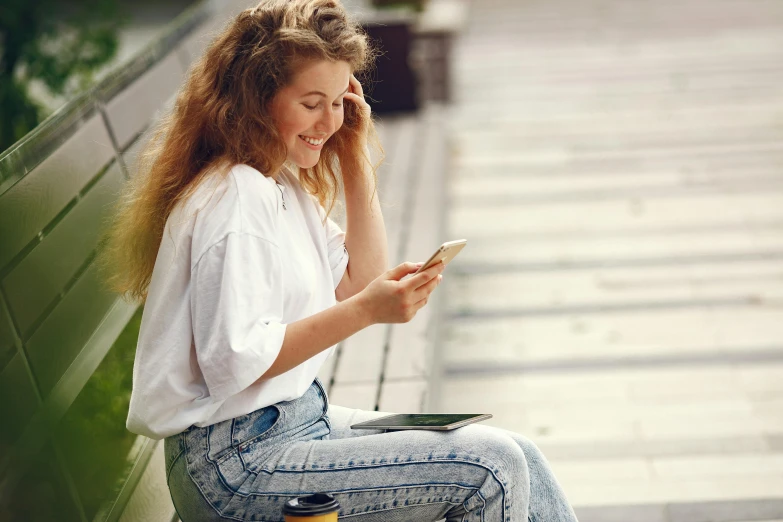 a woman sits on the bench holding her cell phone