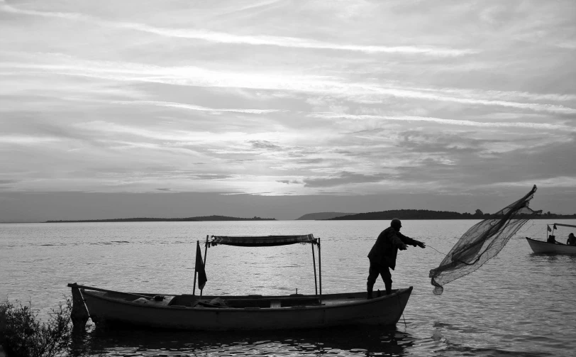 black and white pograph of man standing on a boat