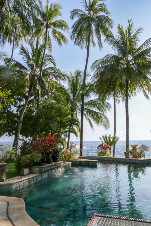 a pool area is situated in front of a tropical beach