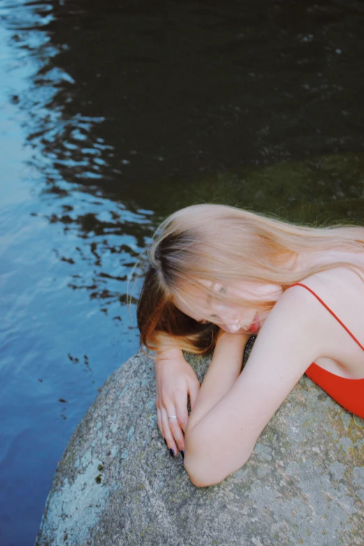 a beautiful young woman sitting on top of a rock