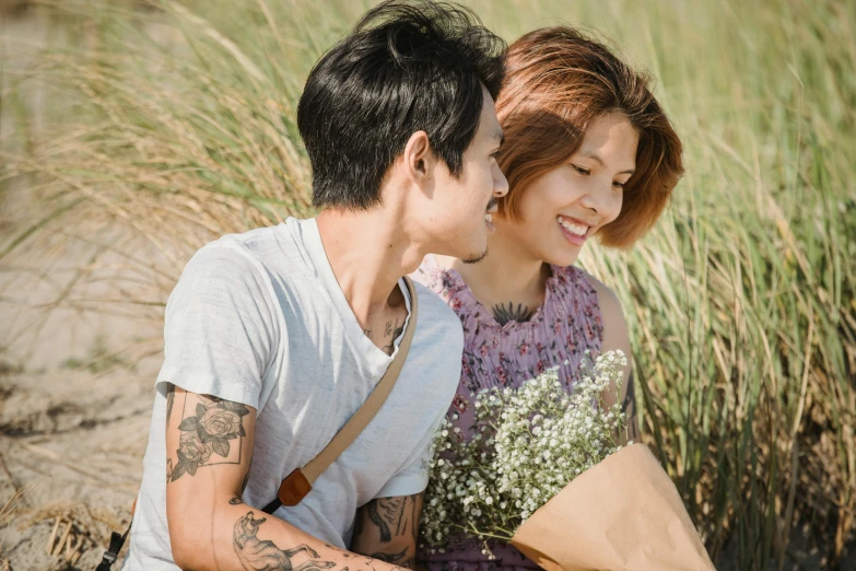 a young man is sitting next to a woman and holds his neck as she smiles