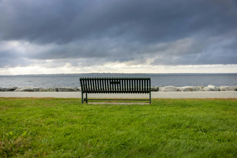 this bench is sitting on the grass next to the ocean