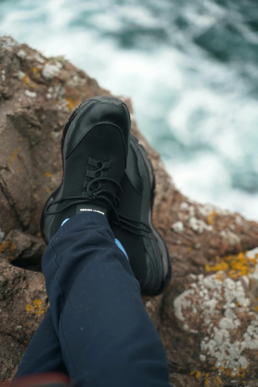 someone in black shoes with their feet on a rock