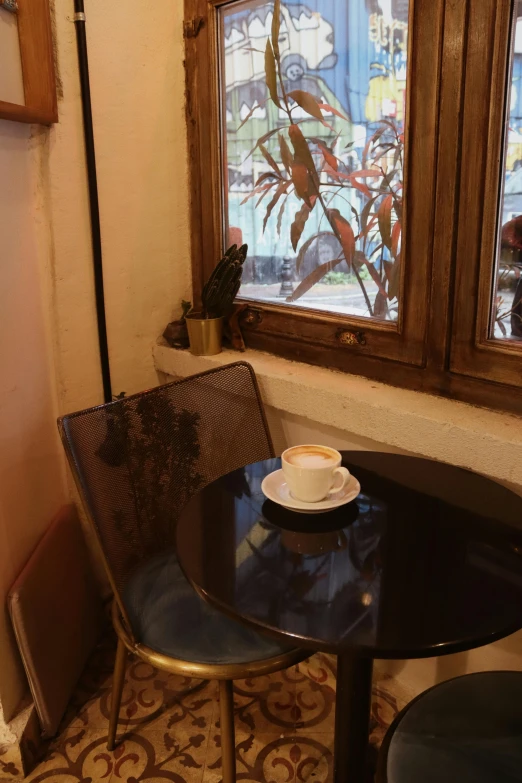 a cup of coffee on a saucer sitting near a window