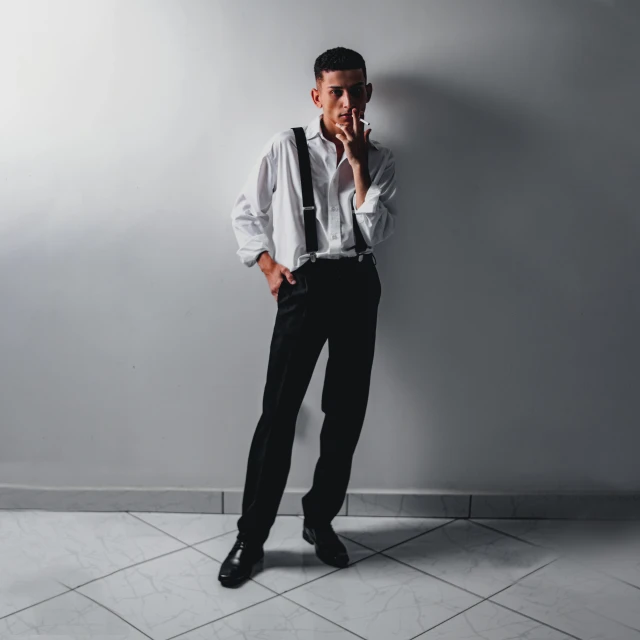 man standing against a wall talking on a cellphone