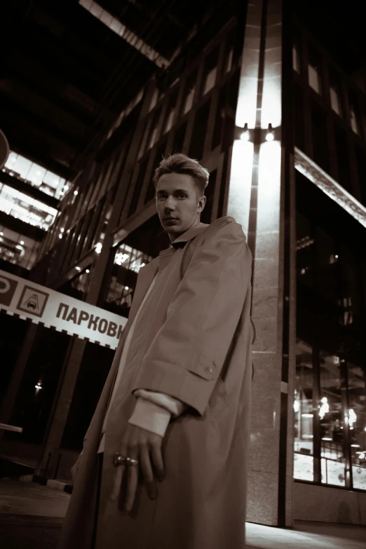 a man wearing a long coat standing next to a street sign