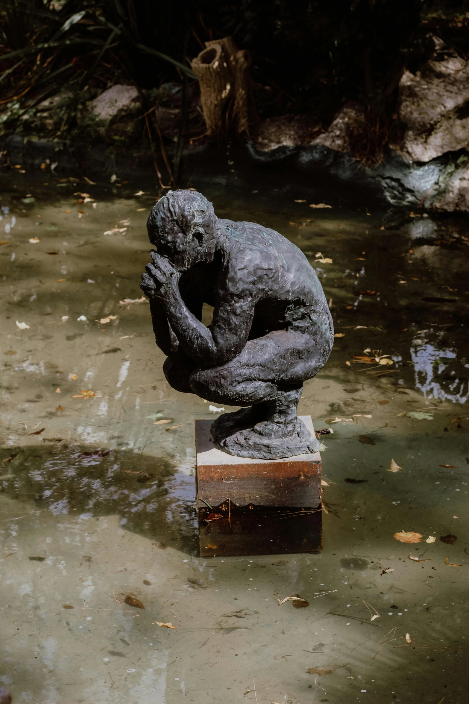 a statue sitting on top of a block in the water